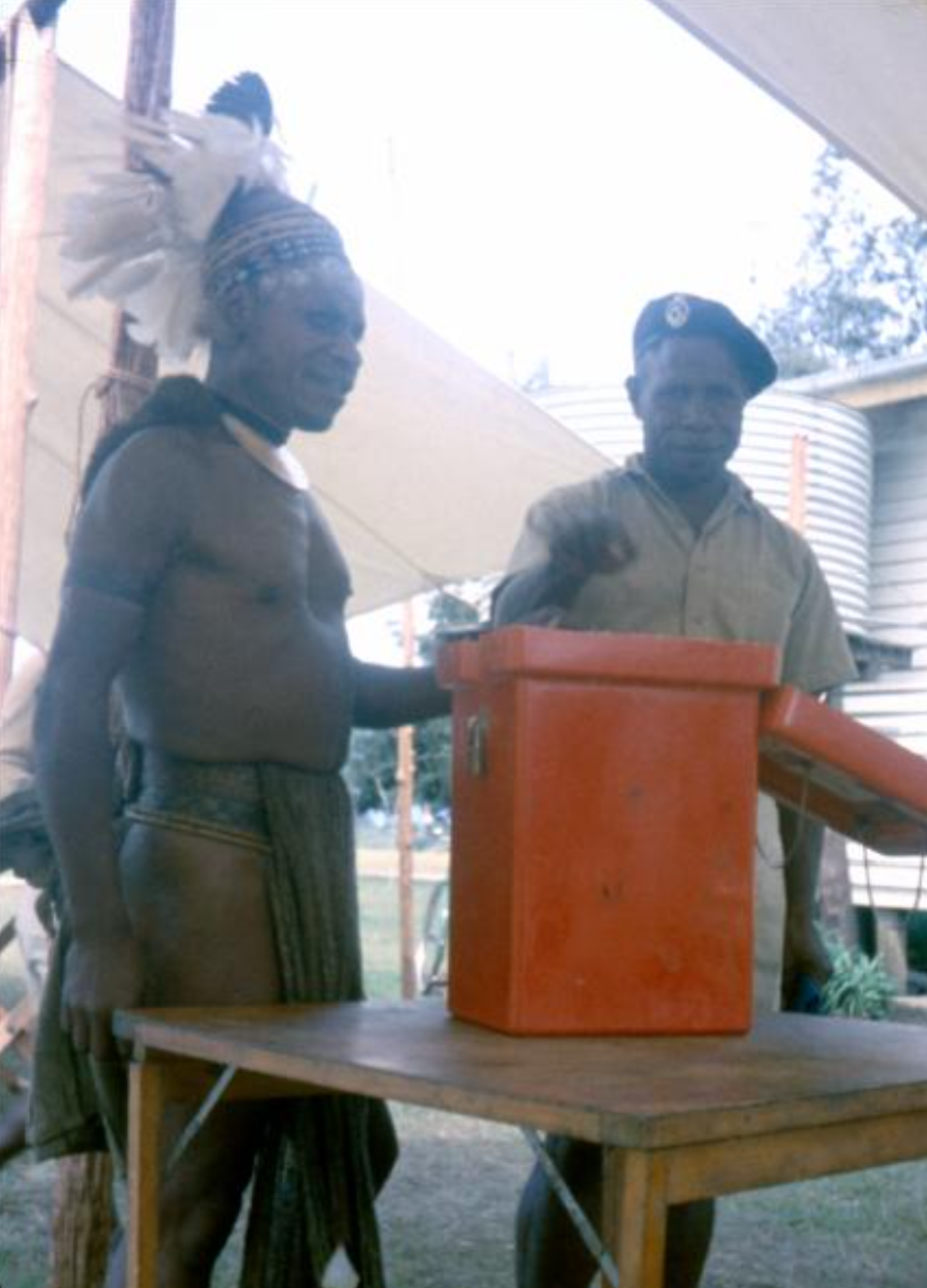Man in ceremonial dress with feather headdress voting.