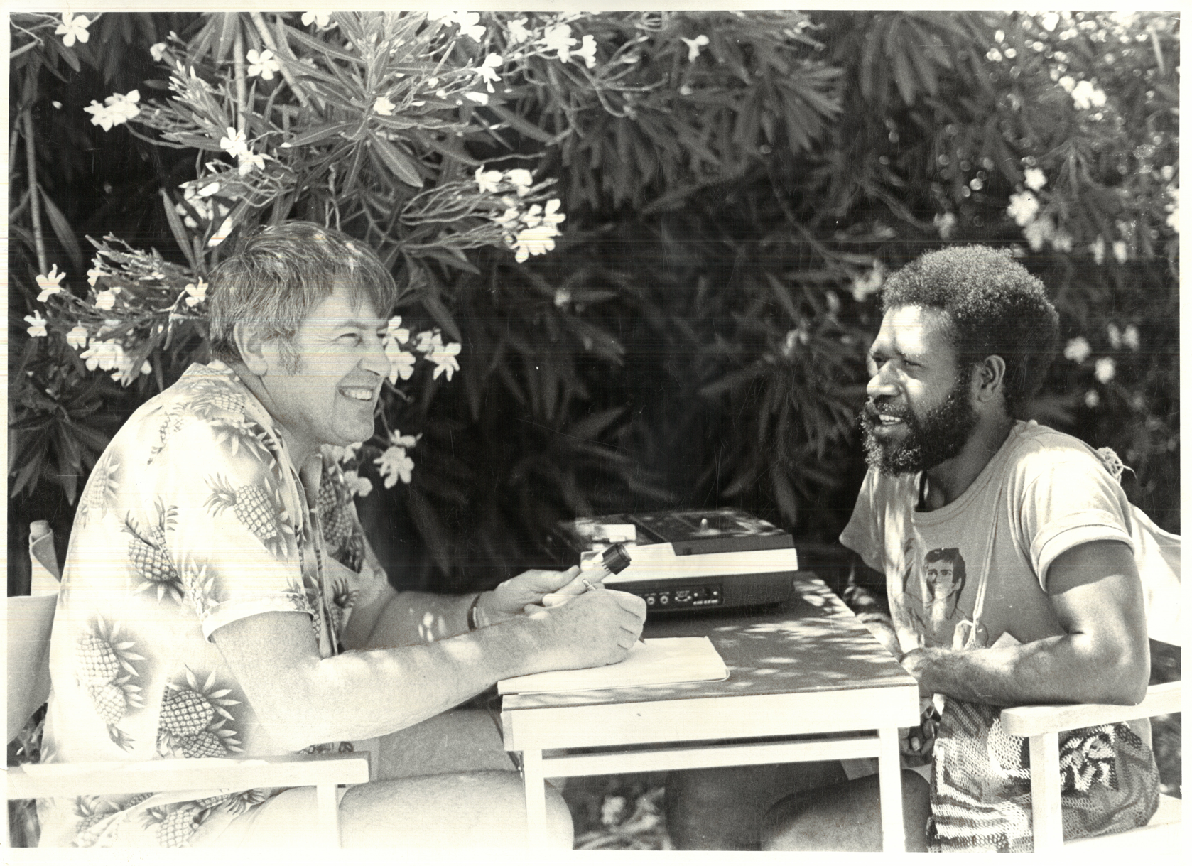 Two men sitting at a table with sound reel recording equipment