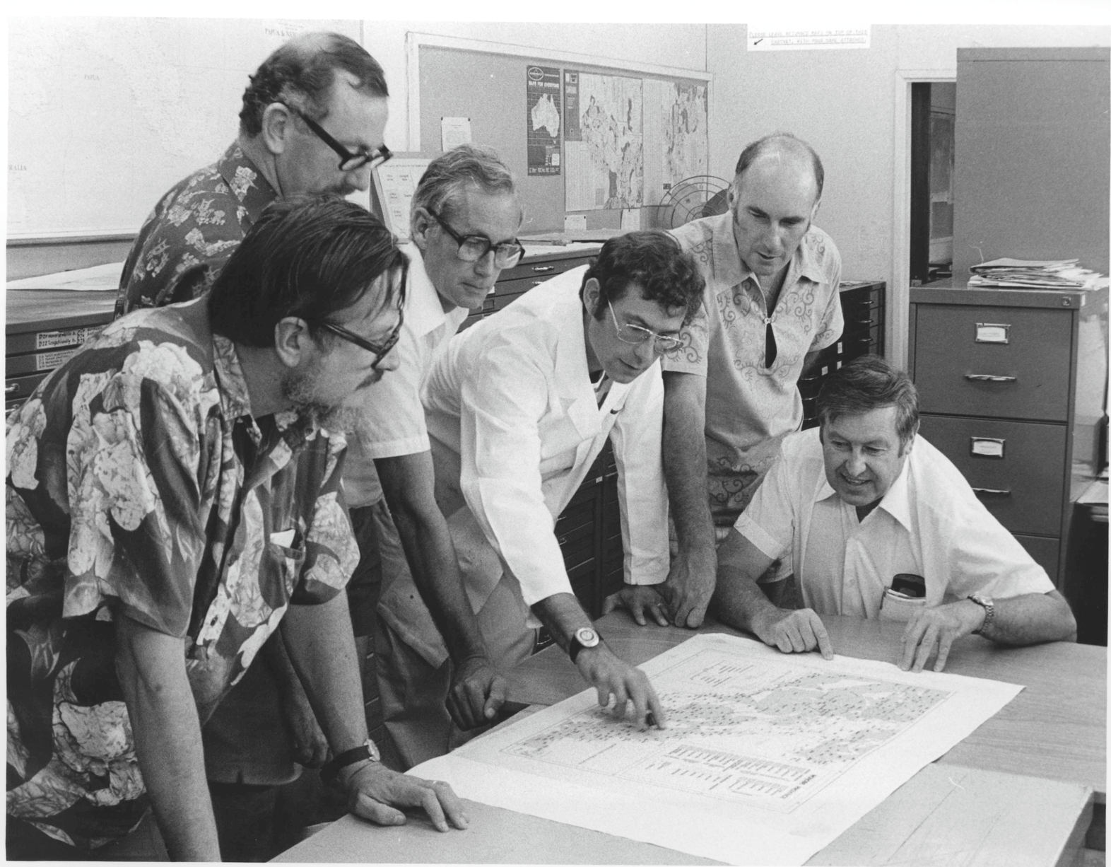 Black and white photograph of men at table with map
