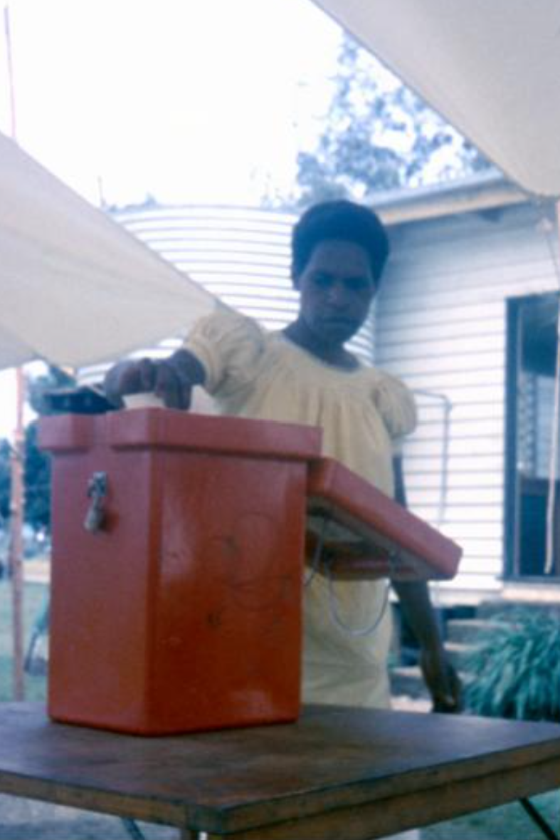 Woman placing ballot in red ballot box