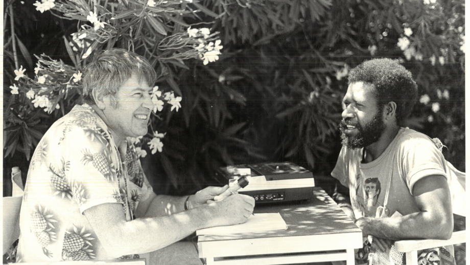 Two men sitting at a table with sound reel recording equipment