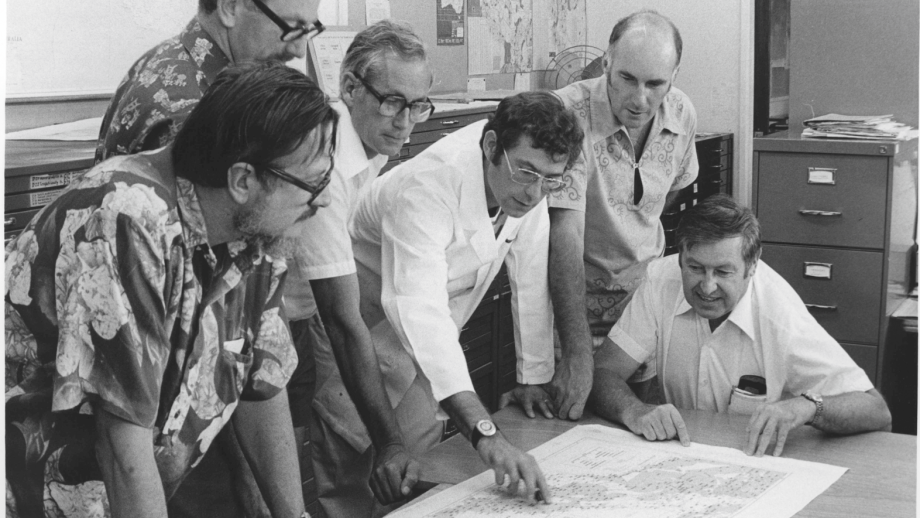 Black and white photograph of men at table with map
